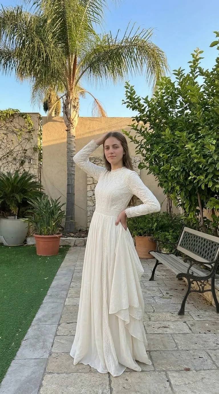 שמלת כלה או ערב בגוון שמנת עם חלק עליון ושרוולים ארוכים העשויים תחרה עדינה בעלת דוגמאות גיאומטריות וצווארון גבוה. השמלה בעלת חיתוך במותן וחצאית ארוכה ונשפכת המשלבת עיטורי תחרה אנכיים ושכבות בד מדורגות ואסימטריות בצד אחד.