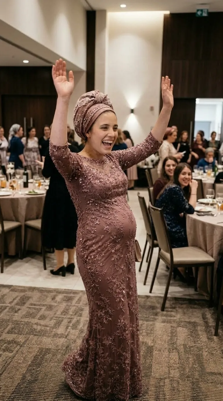 שמלת ערב ארוכה בגוון ורוד עתיק בגזרה צמודה, המכוסה כולה בתחרה עשירה עם עיטורי פרחים ושיבוץ פאייטים מנצנצים. לשמלה שרוולי שלושה-רבעים עם סיומת תחרה עדינה וצווארון עגול המשלב בד רשת שקוף בחלקו העליון של המחשוף.