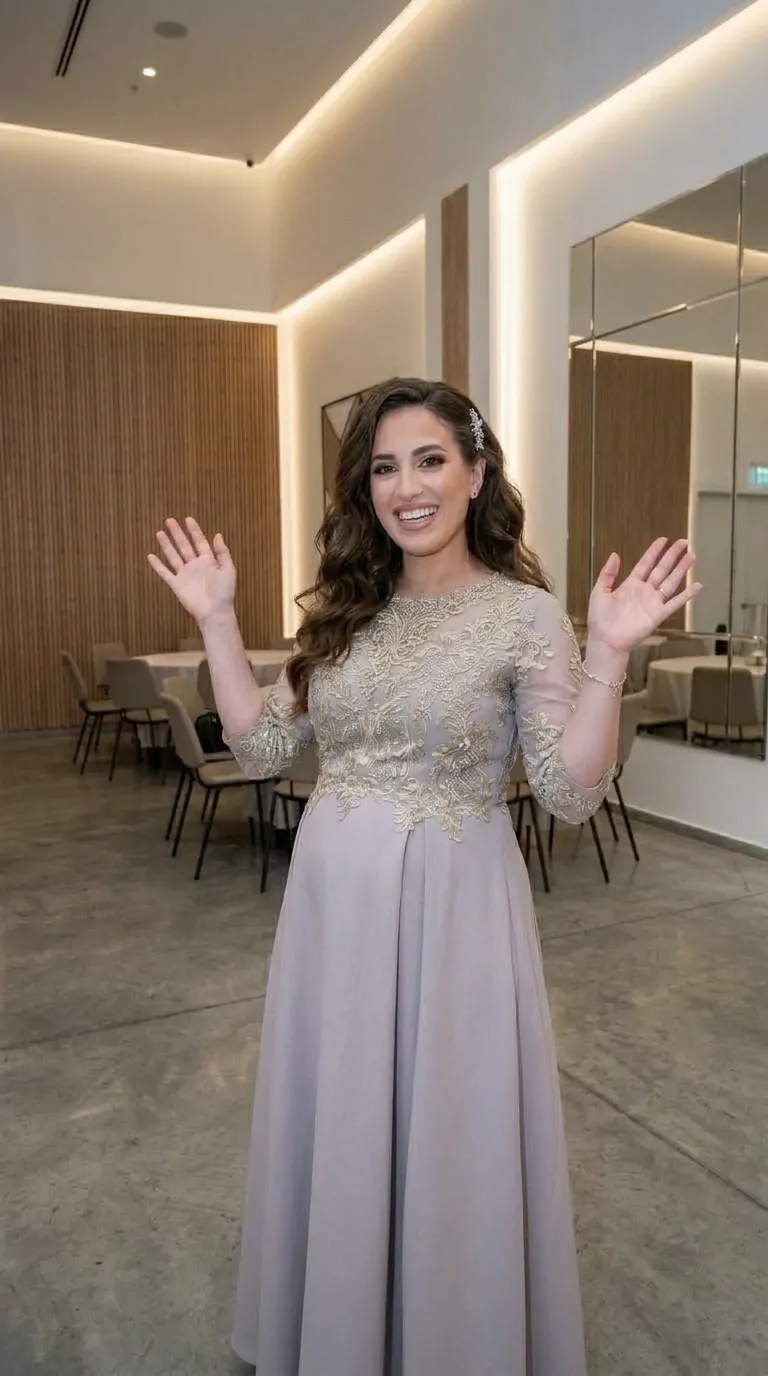שמלת ערב בגוון סגול בהיר עם חצאית ארוכה בגזרת A נשפכת, המחוברת לחלק עליון מעוטר באפליקציות תחרה זהובות בדוגמאות פרחוניות. השמלה כוללת מחשוף עגול וגבוה ושרוולים באורך שלושת-רבעי העשויים בד רשת שקוף למחצה המעוטר בתחרה תואמת.